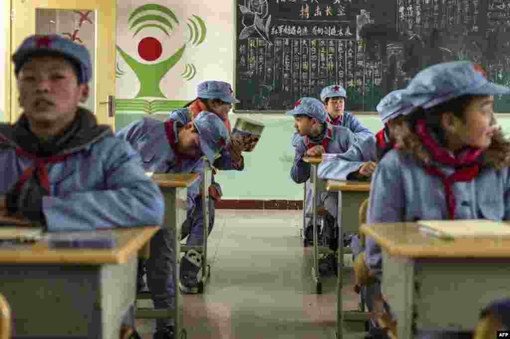 2014年1月21日,中国四川省北川市的北川红军小学,穿着制服的儿童聚集在他们的教室里。黑板上有“红军创造奇迹 我们创造未来”的口号,也有用于修身的《老子·道德经》里的话。