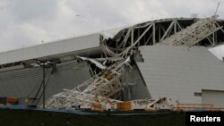 Para pekerja bangunan berdiri di dekat sebuah derek yang rubuh di station Sao Paulo (27/11). Stadion yang dikenal sebagai "Itaquerao" ini akan menjadi tuan rumah Piala Dunia (World Cup) 2014.