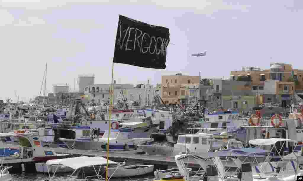 A black flag with writing reading in Italian "Vergogna" (shame) waves in the harbor of the island of Lampedusa, Italy, Oct. 4, 2013.