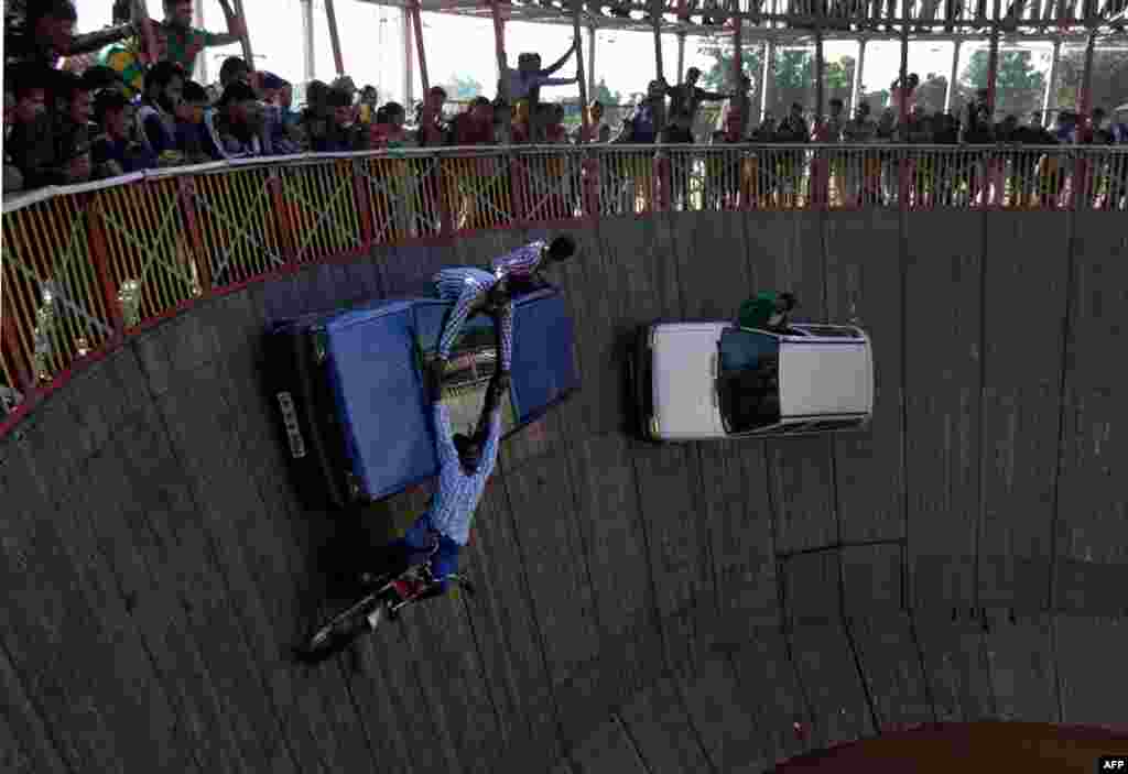 Indian performers ride cars and motor bikes inside a makeshift wooden cylindrical 'Wall of Death' during the annual Farmers' Fair at Shama Chak Jhiri, some 22 kilometers from Jammu.