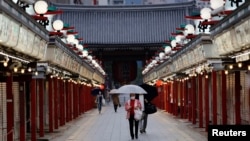 東京市民戴著口罩走在關閉的商店旁。（2021年5月7日）