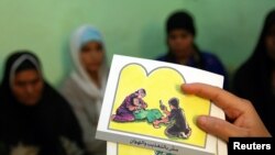 Seorang konselor memegang kartu yang digunakan untuk mendidik perempuan tentang mutilasi alat kelamin perempuan (FGM).