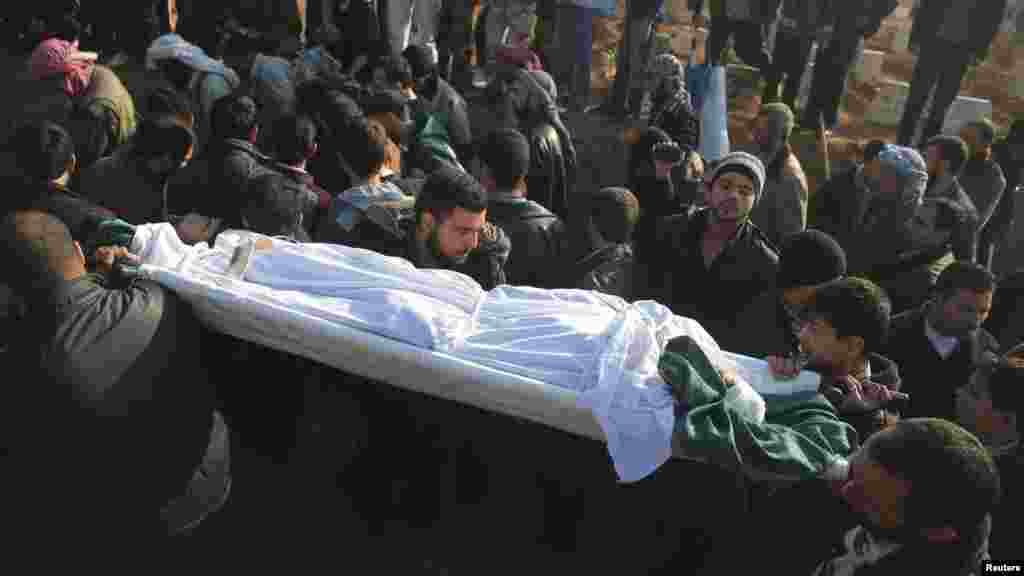 People carry the body of a civilian activist killed during what activists said was an ambush, during a funeral in eastern al-Ghouta, near Damascus, Nov. 24, 2013.