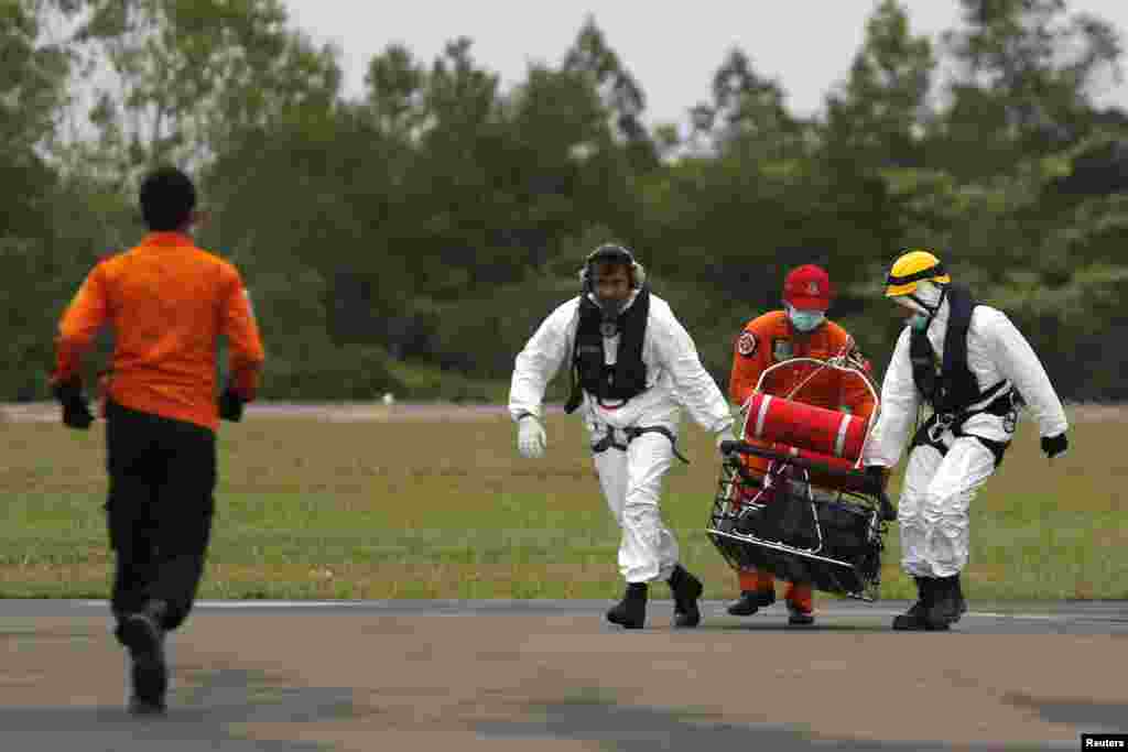Para anggota tim penyelamatan mengangkut jenazah seorang korban AirAsia penerbangan 8501 di pangkalan udara Iskandar, Pangkalan Bun (6/1). (Reuters/Beawiharta)