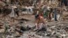 Seorang pria mencuci pakaiannya di sungai dekat puing-puing yang tersisa setelah air banjir meluluhlantakkan Desa Nanxinfang di pinggiran Beijing, Jumat, 4 Agustus 2023. (Foto: AP)