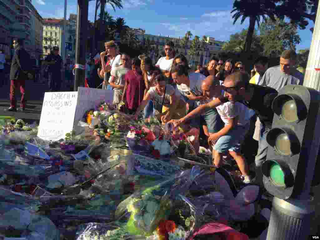 People gather where flowers and mementos have been laid in honor of the victims of the Bastille Day truck attack in Nice, France, July 15, 2016. (Photo: VOA Persian Service)