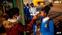 Seorang petugas mengukur suhu tubuh seorang murid SMP Winnie Mandela sebelum masuk ke kelasmya di kota Tembisa, Ekurhuleni, Afrika Selatan, 8 Juni 2020. (Foto: dok).