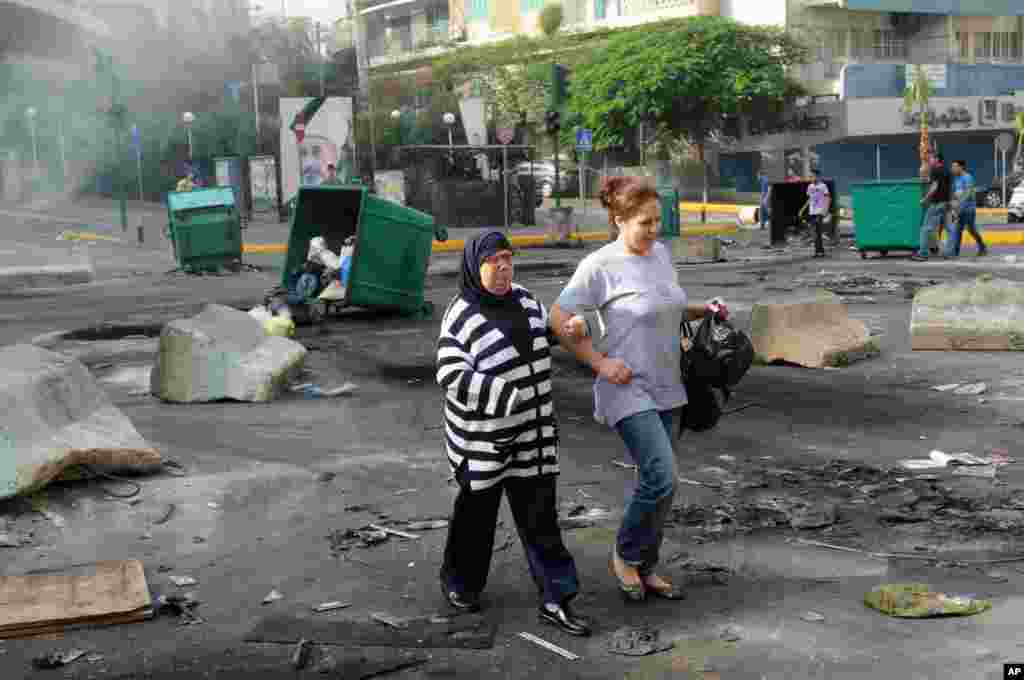 Women walk through a road block of burning garbage containers laid by Sunni protesters angry at the killing of Brig. Gen. Wissam al-Hassan in Beirut, Lebanon, October 20, 2012.