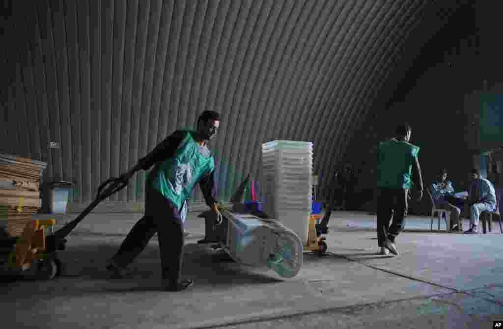 Afghan election workers in a warehouse carry ballot boxes and election materials, in Kabul, June 13, 2014. 