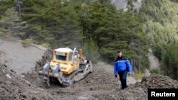 French Gendarme Bruno Hermignies stands by a bulldozer clearing a path to the crash site of the Germanwings Airbus A320 in the mountains, near Seyne-les-Alpes, French Alps, March 30, 2015. 