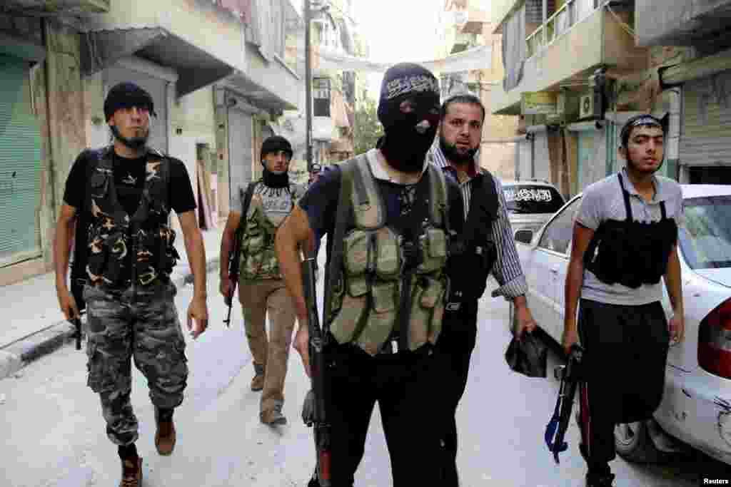 Free Syrian Army fighters carry their weapons as they walk along a street prior to an offensive against forces loyal to Syria's President Bashar al-Assad, in Aleppo's Salaheddine neighborhood, July 6, 2013.