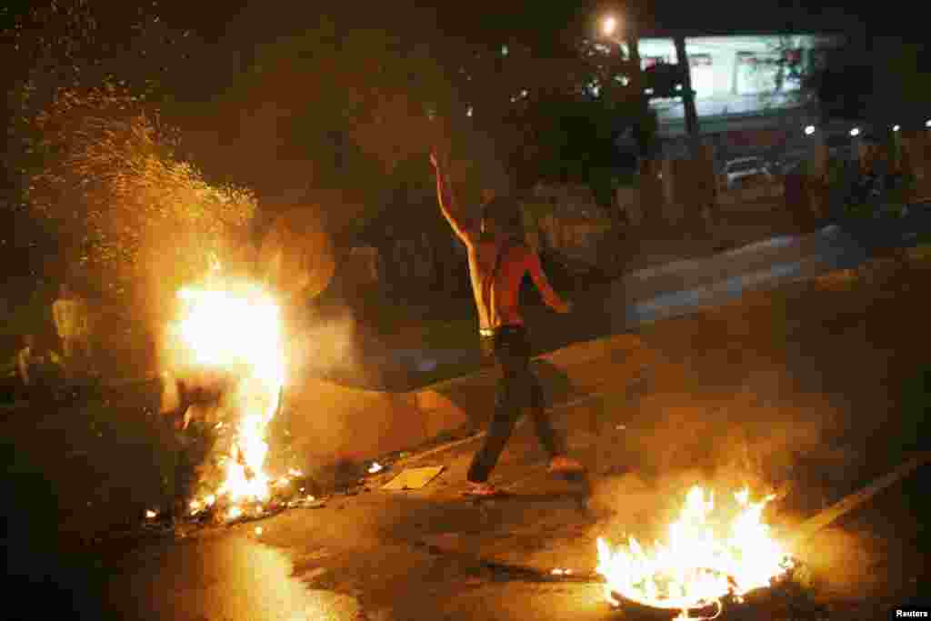 A protester gestures between flames during clashes with security forces in Phnom Penh, Sept. 15, 2013.