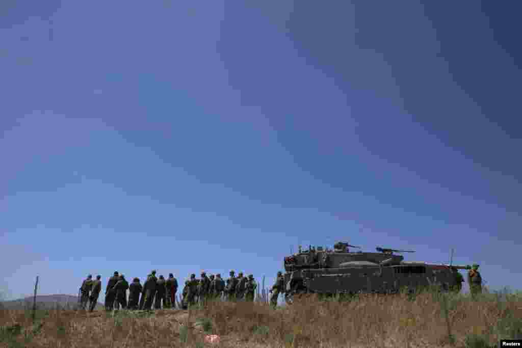 Israeli soldiers stand next to a tank near Alonei Habashan on the Israeli occupied Golan Heights, close to the ceasefire line between Israel and Syria, June 22, 2014.