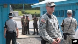 FILE - In this July 27, 2014, file photo, North Korean army soldiers watch the south side while South Korean, left, and U.S. Army soldiers stand guard at the truce villages of Panmunjom in Paju, South Korea. 