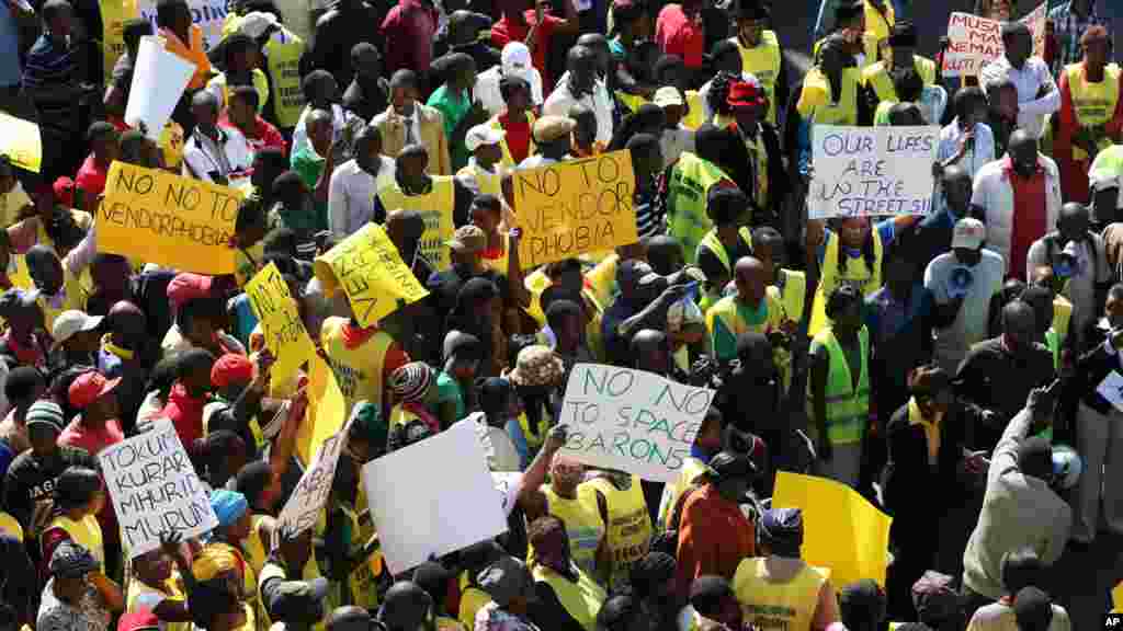 Des vendeurs de rue zimbabwéennes tiennent des banderoles, lors d'une manifestation à Harare, exhortant le gouvernement à cesser de les chasser, le mercredi juin 24, 2015