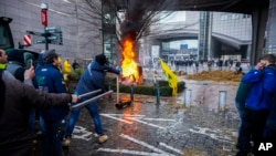 Para petani membakar sampah dan ban saat menggelar demonstrasi di luar Parlemen Eropa di tengah berlangsungnya KTT Uni Eropa di Brussels, Kamis, 1 Februari 2024. (Foto: AP)