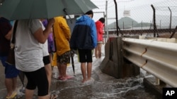 People play with overflown water caused by Typhoon Nida in Hong Kong, Tuesday, Aug. 2, 2016.