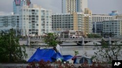 FILE - Tents stand on the other side of the shore of Laguna de Condado opposite the exclusive area of ​​Paseo Caribe in San Juan, Puerto Rico, Oct. 23, 2017. 