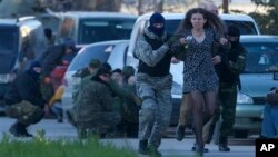 Anggota milisia pro-Rusia mengevakuasi warga saat pasukan Rusia menyerang pangkalan udara Belbek, di luar Sevastopol, Krimea, Sabtu (22/3). (AP/Ivan Sekretarev)