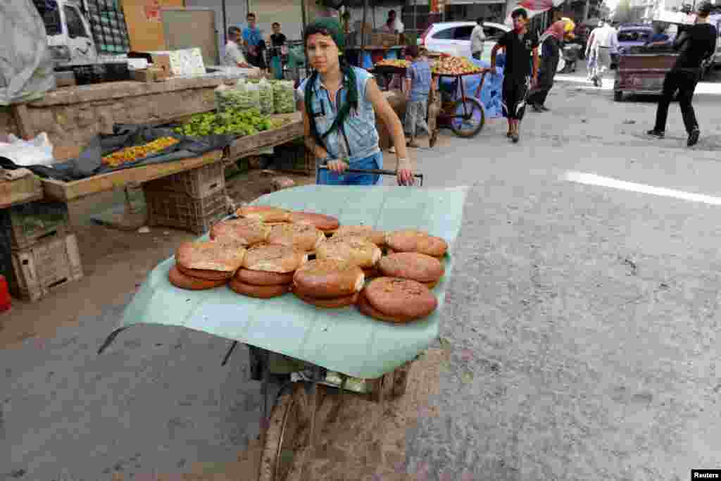 A boy sells sweet bread on the first day of the holy fasting month of Ramadan, in the Al-Fardous neighborhood of Aleppo, Syria, June 29, 2014.