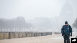 一位华盛顿居民冒雪去上班。他身后的建筑是美国国会大厦