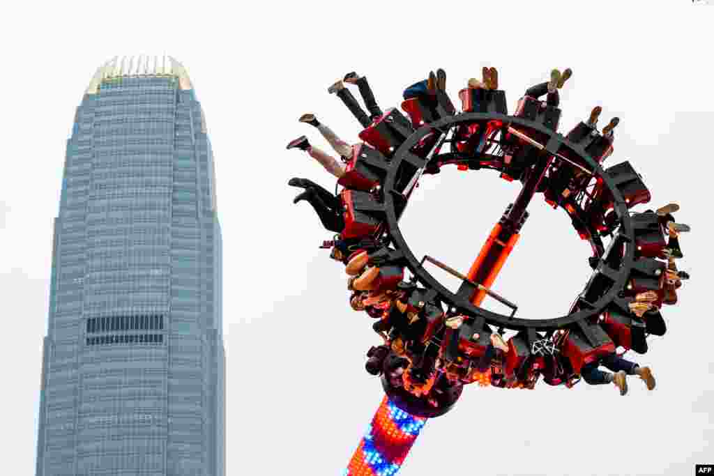 People ride a Luna Park's Sledgehammer in front of the International Financial Centre (IFC) tower in Hong Kong.