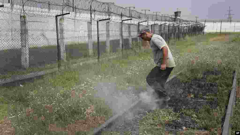 A prisoner tramples smoldering grass in a high-security facility after shelling in Donetsk, eastern Ukraine, Aug. 11, 2014.