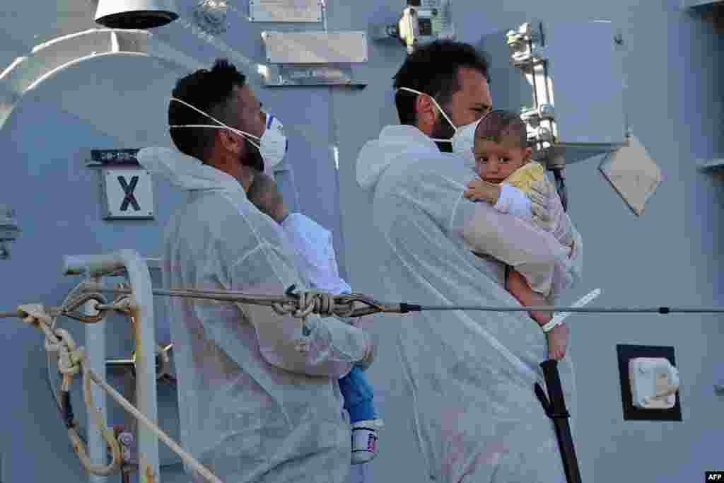 Rescuers holds babies as the Italian military ship "Chimera" - with around 350 would-be immigrants onboard - arrives in the port of Pozzallo, Sicily, one day after a rescue operation off the coast of Sicily.