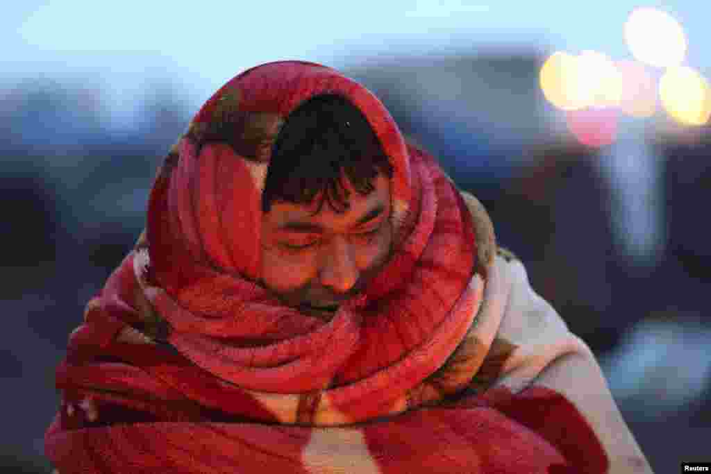 Seorang imigran Afghanistan menggunakan selimut untuk menutupi kepalanya dalam cuaca yang dingin di Calais, Perancis utara.