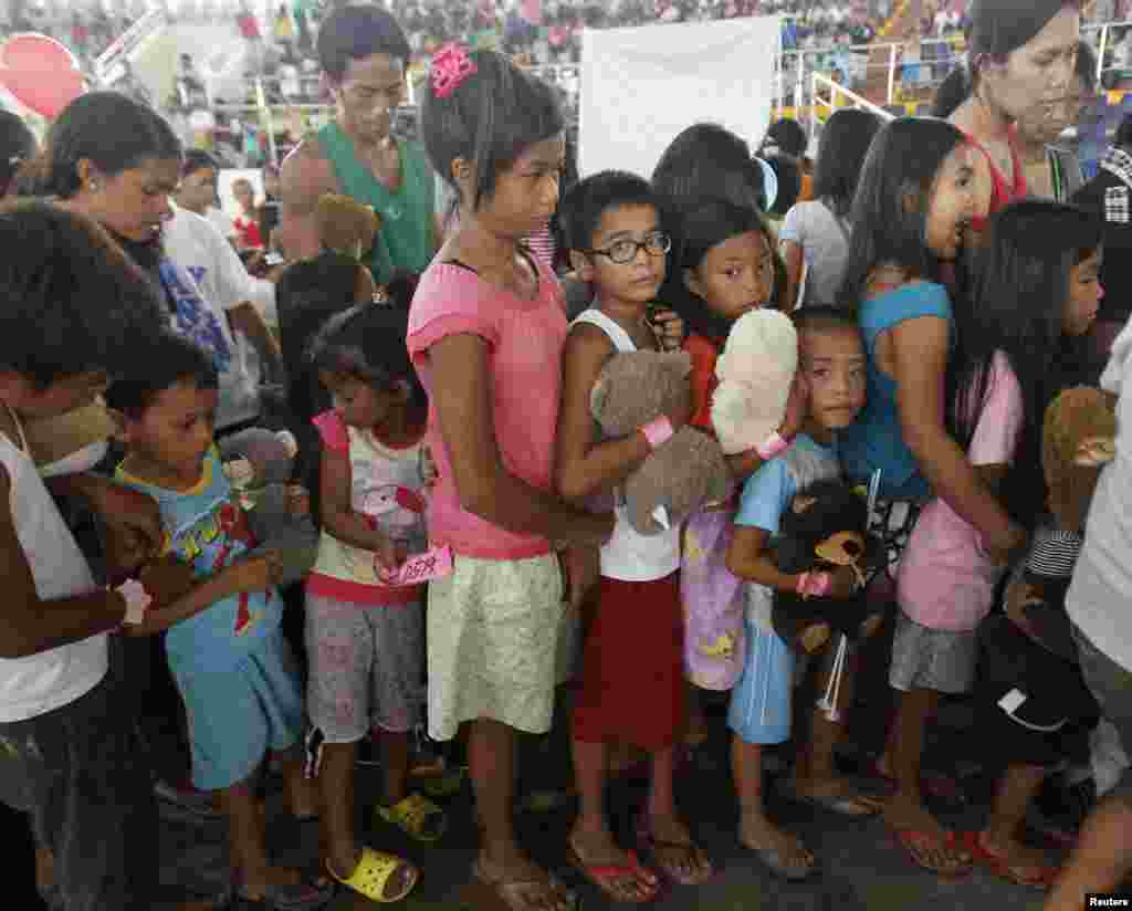 Para korban topan Haiyan antri dalam program pemberian hadiah di sebuah aula di kota Tacloban, Filipina.
