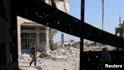 Un combatiente del Ejército Sirio Libre camina entre las ruinas de la ciudad sureña de Dera el 9 de julio.