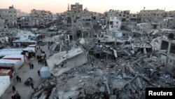 Palestinians walk among the rubble of buildings, In Khan Younis