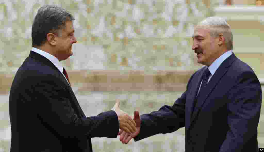Presiden Belarus Alexander Lukashenko (kanan) dan Presiden Ukraina Petro Poroshenko berjabat tangan di Minsk (11/2). (AP/Sergei Grits)