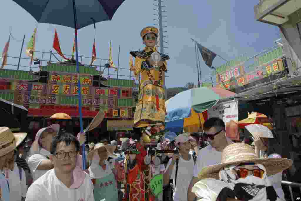 ក្មេងម្នាក់ស្លៀកពាក់ប្រពៃណីចិនត្រូវអណ្តែតលើអាកាសអំឡុងការហែក្បួននៅកោះ Cheung Chau ទីក្រុងហុងកុងដើម្បីអបអរពិធីបុណ្យ Bun។