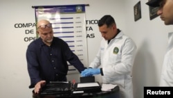 Un policía toma huellas dactilares al excomandante de las Autodefensas Unidas de Colombia (AUC), Salvatore Mancuso, luego de llegar a Colombia desde Estados Unidos, en el Comando Aéreo de Transporte Militar (CATAM) en Bogotá, Colombia, el 27 de febrero de 2024.