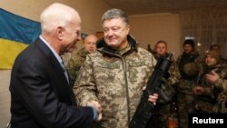 Ukrainian President Petro Poroshenko (R) shakes hands with U.S. Senator John McCain during a meeting with Ukrainian servicemen in Shirokino settlement near Mariupol, Ukraine, Dec. 31, 2016.