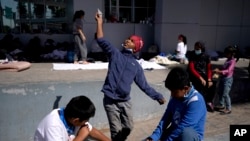 Seorang bocah migran, tengah, meluncurkan pesawat kertas saat bermain dengan anak-anak migran lainnya di alun-alun dekat titik masuk Jembatan Internasional McAllen-Hidalgo ke AS, setelah tertangkap basah mencoba menyelinap ke AS dan dideportasi. (Foto: AP)