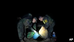 ARCHIVO - La policía antinarcóticos inspecciona el uso de químicos en la producción de base de coca antes de quemar un laboratorio en una zona rural de Orito, estado de Putumayo, Colombia, en abril de 2022.