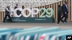 Peserta melewati papan tanda KTT Iklim PBB COP29 di Baku, Azerbaijan, 23 November 2024. (Foto: AP)