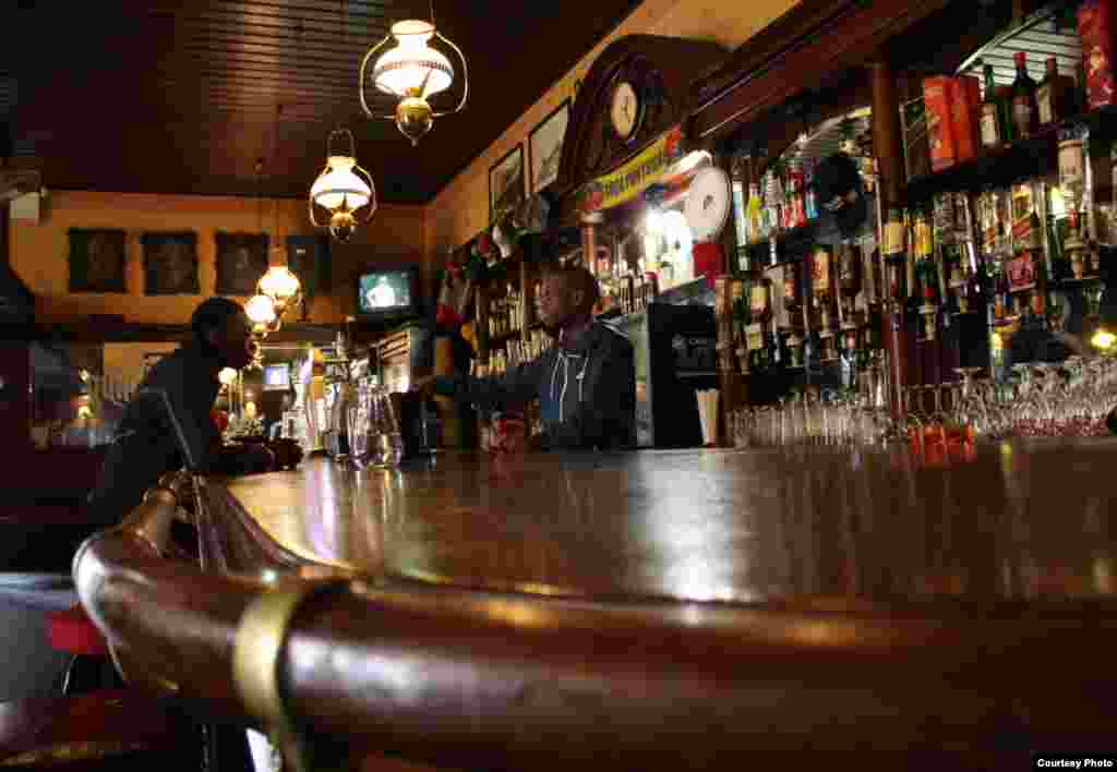 Decades of regulars put a sheen on the wood and brass bar where Thokozane Nxumalo serves clients of The Guildhall, Johannesburg's oldest bar. Photo by Darren Taylor