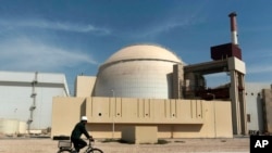 Seorang pekerja mengendarai sepeda melintas di depan reaktor pembangkit listrik tenaga nuklir Bushehr di Kota Busher, Iran, 26 Oktober 2010.