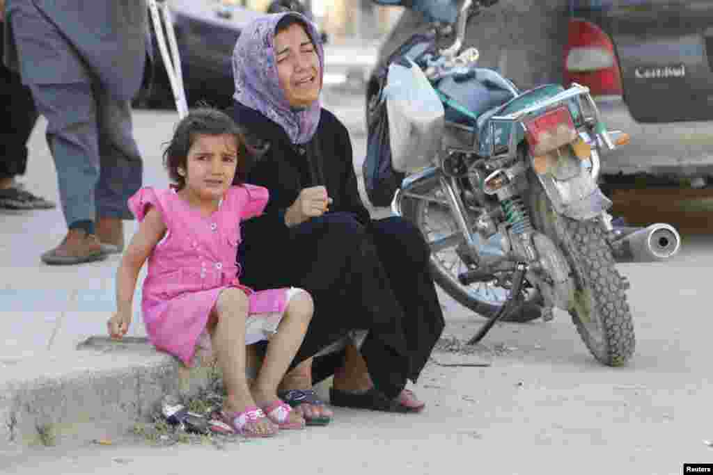 A woman and a girl react after, according to activists, two barrel bombs were thrown by forces loyal to President Bashar Al-Assad, in Hullok neighborhood, Aleppo, May 1, 2014. 
