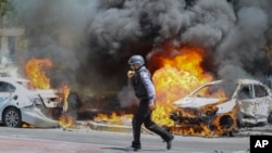 Seorang petugas pemadam kebakaran Israel berjalan di samping mobil yang terkena rudal yang ditembakkan dari Jalur Gaza, di kota Ashkelon di Israel selatan, Selasa, 11 Mei 2021. (AP Photo / Ariel Schalit)
