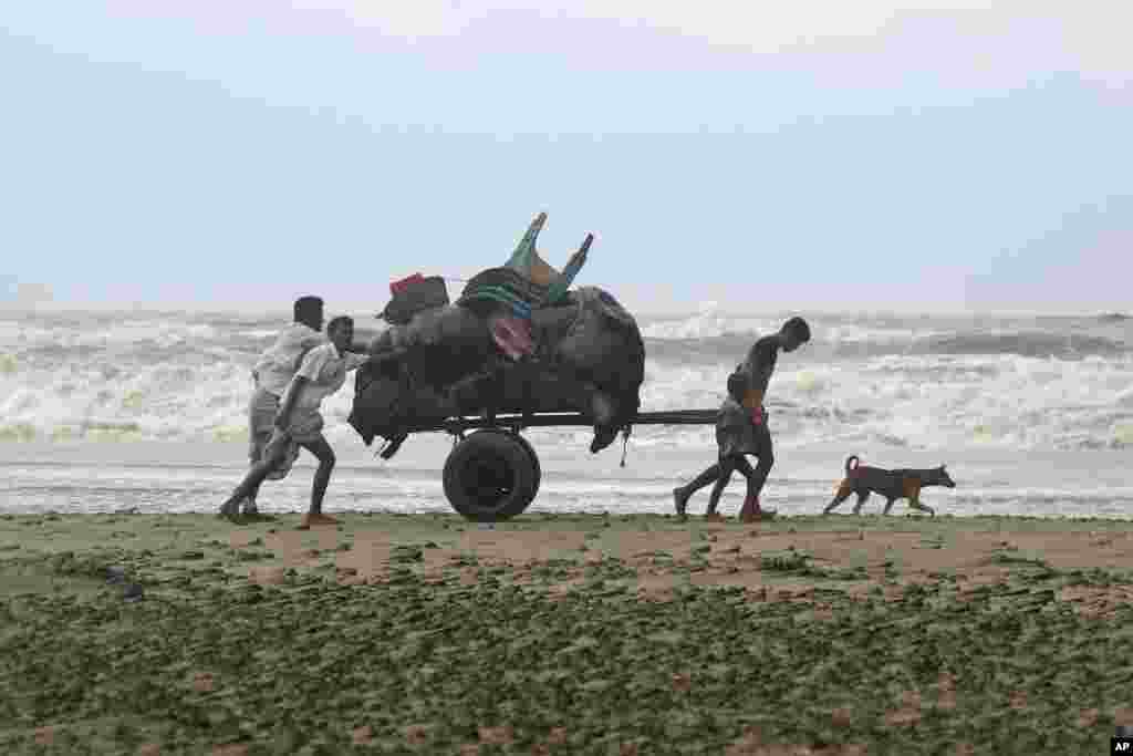 Bangladeshis push a cartload of belongings and walk back home after spending a night at a shelter in Cox's Bazar, Bangladesh. A tropical storm lashed southern Bangladesh, destroying hundreds of poorly built homes in some remote islands in the Bay of Bengal, officials said.