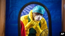 FILE - A health care worker dons protective gear before entering an Ebola treatment center in Freetown, Sierra Leone.
