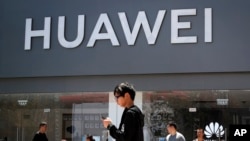 People walk past a Huawei retail store in Beijing, Sunday, June 30, 2019.
