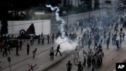 Pakistani protesters hurl back tear gas fired by police, unseen, to stop them from walking toward the U.S. consulate during a demonstration in Karachi, Pakistan, Sunday, Sept. 16, 2012.