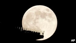 FILE - A supermoon rises behind an observation deck in New York City as seen from Hoboken, NJ, Nov. 15, 2024.