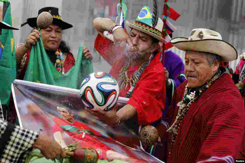 Peruvian shamans perform a ritual while holding the official ball for the 2014 World Cup and a poster of Portugal's soccer player Cristiano Ronaldo at the National Stadium in Lima, June 10, 2014.