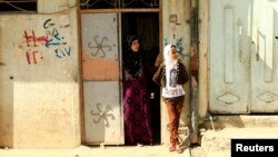 Civilians stand in front of their home in West Mosul, Iraq, July 20, 2017. 